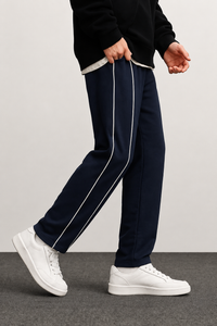 Navy tracksuit with white stripes worn by a person on a plain background