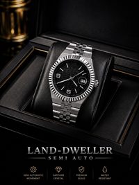 A silver stainless steel wristwatch with a black dial and fluted bezel, displayed on a black cushion inside a black presentation box. The brand name 'LAND-DWELLER' is printed at the bottom with feature icons.