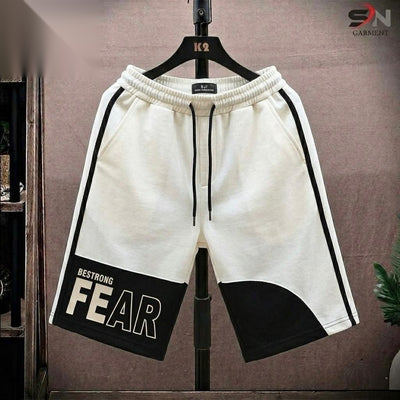 A pair of men's athletic shorts in off-white and black, hanging on a black hanger. The shorts feature a black side stripe, a black lower leg panel with 'BESTRONG FEAR' text, and a black drawstring.