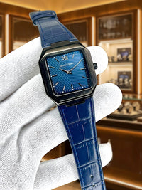 Blue wristwatch with a detailed face held by a white glove against a blurred background.