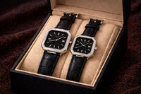 Two black watches in a box on a dark textured background
