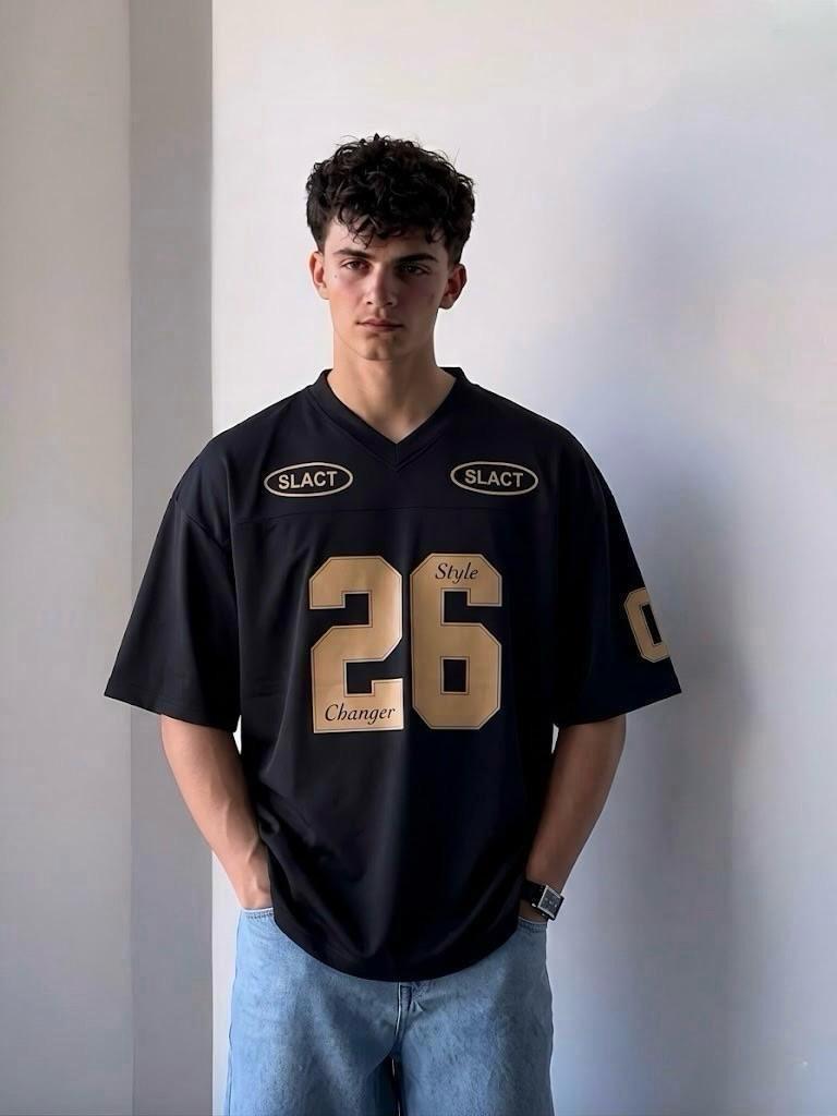 Person wearing a black sports jersey with gold lettering against a plain background