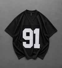 A black short-sleeve athletic jersey with a large white '91' printed on the front, laid flat on a dark gray background.