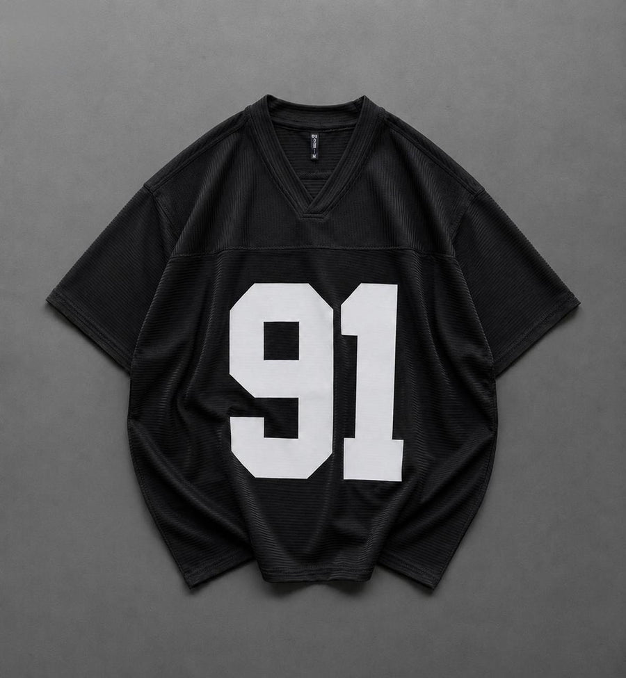 A black short-sleeve athletic jersey with a large white '91' printed on the front, laid flat on a dark gray background.