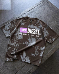 A brown and gray distressed camouflage t-shirt with a prominent 'DIESEL DENIM DIVISION' logo on the chest, laid flat on a gray stone surface.
